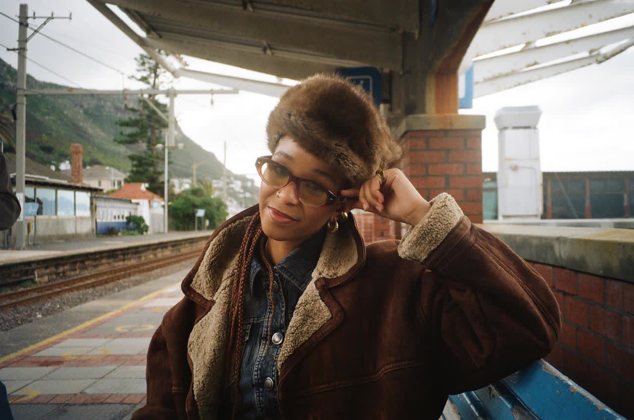 Woman in a fur hat and shearling-collar jacket on a Cape Town station platform